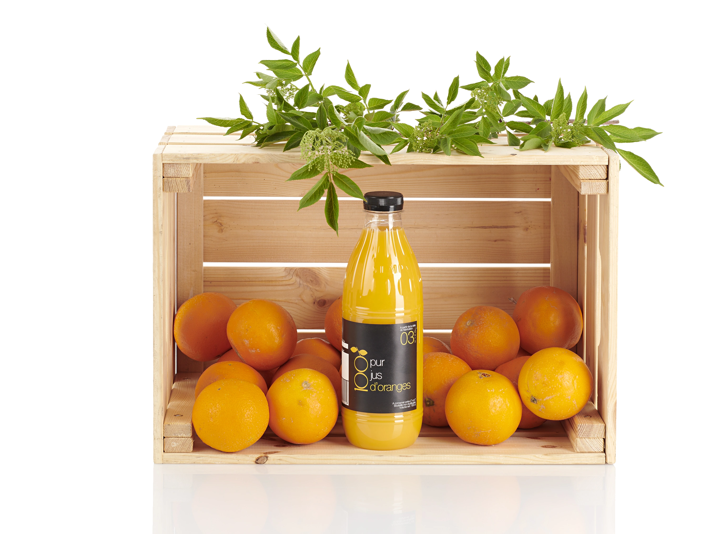 Bouteille de jus et oranges présentées dans une caisse en bois